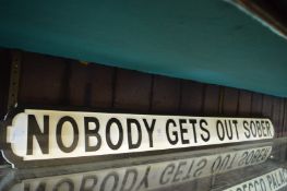 A novelty carved wood and painted sign 'Nobody gets out sober'.