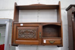 An Edwardian walnut hanging shelf with small carved cupboard door and drawer.