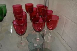 Twelve cranberry coloured wine glasses.
