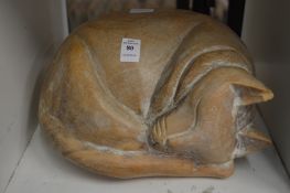 A carved wood model of a sleeping cat.