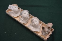Three Lladro cherub heads and a Lladro dog.