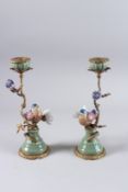 A PAIR OF BIRD AND FLOWER PORCELAIN AND GILT METAL CANDLESTICKS on circular bases.