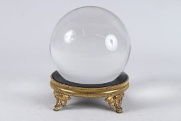 A MYSTIC CRYSTAL BALL, 5.5ins diameter, on a Empire circular metal stand.