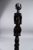 AN ETHNIC CARVED WOOD WALKING CANE, the handle carved with a figure. 39ins long.