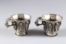 A SMALL PAIR OF CHINESE WHITE METAL OCTAGONAL CUPS. 2.75ins.