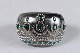 A DECORATIVE DIAMANTE BANGLE with green stones.