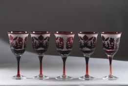 A SET OF FIVE BLACK DECORATED WINE GLASSES.