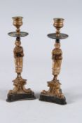 A PAIR OF KATE GREENAWAY CIRCULAR METAL CANDLESTICKS on triangle marble bases. 9.5ins high.
