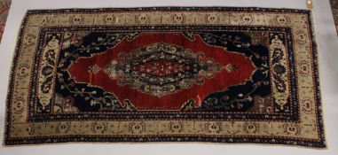 A PERSIAN RUG, in red and blue with central motif. 8ft x 3ft 10ins.