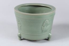 A CELADON CIRCULAR BRUSH POT on three legs. 6ins diameter.
