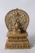 A GILT BRONZE BUDDHA on a stand. 11ins high.