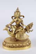 A CHINESE GILDED BRONZE FIGURE OF A FEMALE DEITY, seated on a phoenix and lotus base. 23cms high.