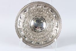 AN INDIAN CIRCULAR WHITE METAL DISH with panels of animals, birds and fish. 12ins diameter.