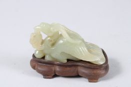 A 19TH CENTURY CHINESE JADE CARVING OF A PHOENIX, with hardwood stand. 4ins long.