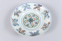A CHINESE DOUCAI PORCELAIN CIRCULAR DISH, painted with flowers and various objects. 20cms diameter.
