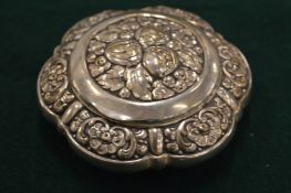 An embossed white metal pill box.