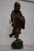 A Chinese carved root wood figure of a sage standing on a jadeite rock.