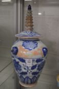 A Chinese blue and white vase with temple style finial to the lid.