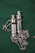 Two police whistles with chains.