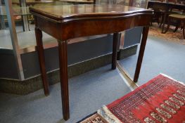 A George III mahogany concertina action fold-over card table of shaped serpentine outline with plain