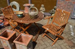 A folding circular hardwood table and pair of folding chairs.