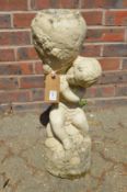 A reconstituted stone planter modelled as a cherub holding an urn.