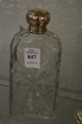 A cut glass scent bottle with silver top.