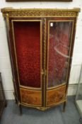 A mahogany and ormolu mounted bow fronted vitrine cabinet with decorative panel doors (one glazing