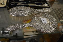 A silver dressing table mirror and hand brush.