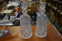 A pair of cut glass decanters with different stoppers.