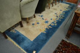 A Chinese carpet, beige ground within a blue border decorated with flowers, 352cm x 270cm.