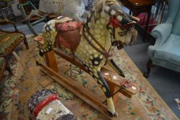 A painted rocking horse on pine stand.