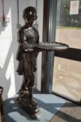 A large impressive cast bronze model of a young man holding a tray.