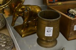 A cast bronze half pint measure and a brass model of an elephant.