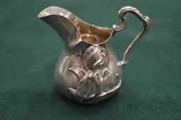 A small embossed silver cream jug.