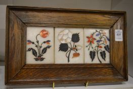 A set of three pietra dura panels depicting flowers mounted in an oak frame.