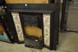 Cast iron fireplace with tile inset panels together with a grate and fender.