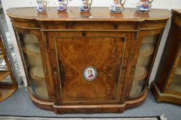 A good Victorian figured walnut credenza, the central door with porcelain portrait plaque, flanked