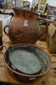 A very large copper jug and two copper dishes.