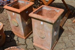 A pair of square shaped terracotta planters.