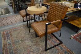 A pair of stylish black painted metal framed armchairs with brown leather upholstery.
