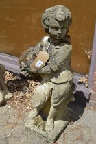 A reconstituted stone garden ornament modelled as a boy holding a basket of flowers.