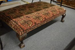 A large stool upholstered with a bokhara carpet.