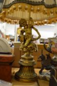 A large gilt metal table lamp modelled as a cherub seated on a pedestal.