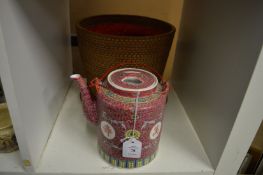 A Chinese famille rose teapot housed in a wicker basket.