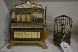 A miniature bird cage clock and a toy one arm bandit.