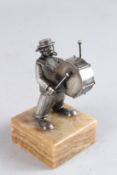 A SMALL SILVER FIGURE OF A MAN playing drums, on a marble base. 4.5ins high.