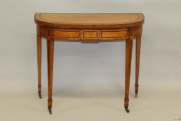 A GEORGE III SATINWOOD CARD TABLE with folding top, green baize cover, on tapering legs with brass
