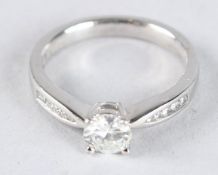 A PLATINUM SINGLE STONE DIAMOND RING, with diamonds to the shoulders.