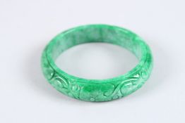 A CARVED JADE BANGLE. 3ins diameter.